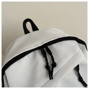 Close-up of waterproof white backpack featuring black zipper and minimal knot puller