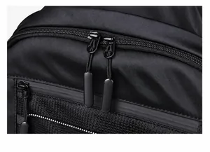Detailed close-up of smooth metal zippers and mesh side pocket on a black nylon backpack