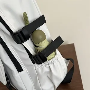 Side view of minimalist white backpack showing water-resistant nylon and side pocket details