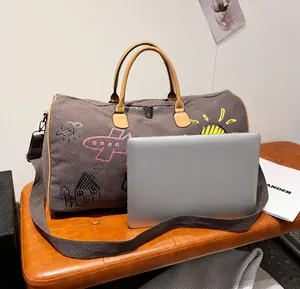 Detailweergave van grijze canvas reistas met graffiti naast een laptop voor de grootte