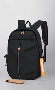 Detail of black backpack showing external USB charging port and orange strap accessory
