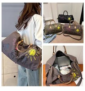 Vue détaillée des sacs de voyage graffiti montrant la grande capacité et la texture toile