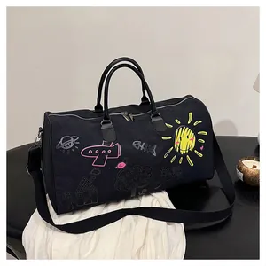 Détail du sac de voyage graffiti noir avec motifs colorés dessinés à la main sur table