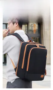 Side view of a large black casual backpack with brown accents worn by a man in a city