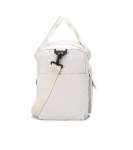 Detail of white quilted travel bag showing adjustable strap and side pocket