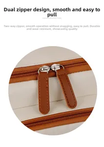Detail of the durable dual-way brown leather zipper pulls on a beige travel backpack
