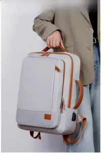 Detail view of a grey commuter backpack with brown leather handles and USB charging port