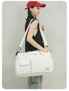 Detail view of the quilted white travel bag showing high-capacity pockets and adjustable strap