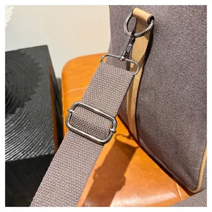 Détail d'un sac en toile avec bandoulière tissée réglable et mousqueton en métal argenté
