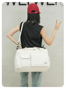 Rear view of a white quilted travel bag with adjustable strap and multi-pocket design