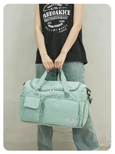 Detail of mint green quilted travel bag with front pockets and waterproof nylon texture