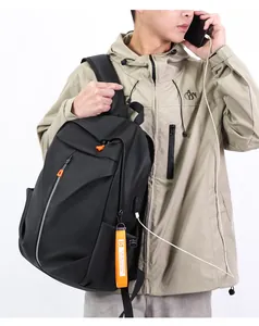 Detail of waterproof black laptop backpack featuring external USB charging port and orange zipper
