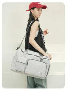 Detail view of light grey quilted travel bag with front pockets and adjustable strap