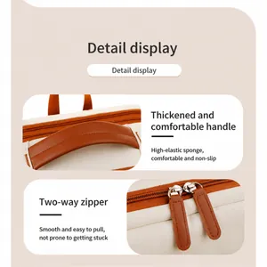 Detail of dual smooth zippers and reinforced padded handle on the beige laptop backpack