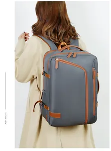 Rear view of a grey waterproof travel laptop backpack shown on a model with a beige coat