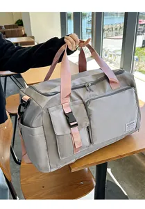 Dettaglio del borsone da viaggio in nylon grigio con manici rosa e fibbie resistenti