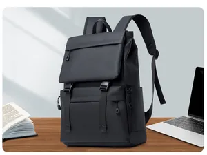 Waterproof black travel backpack on wooden desk next to a laptop and book