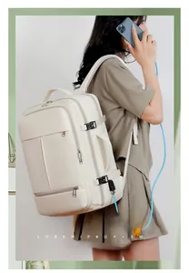 Detail view of cream backpack showing side charging port and multi-layer zippers