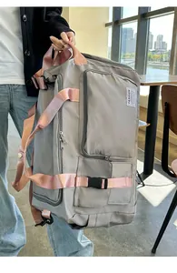 Dettaglio borsa da viaggio grigia con spalline rosa e scomparti multipli con cerniera