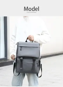 Gray minimalist flap-top backpack shown on model against a clean architectural background