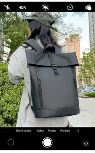 Outdoor shot of a black roll-top backpack with waterproof matte finish and side zippers