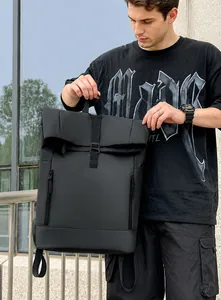 Detail of black waterproof roll-top backpack held by hand featuring functional buckles