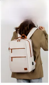 Detail of white laptop backpack featuring USB charging port and brown leather trim accents