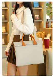 Spacious off-white commuter laptop bag with orange handles and canvas shoulder strap
