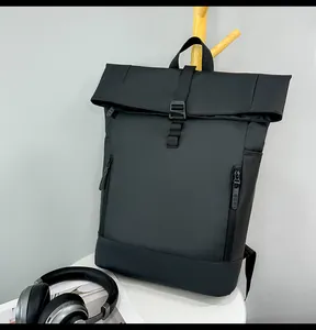 Close-up of black roll-top waterproof backpack with buckle closure and side zipper pockets