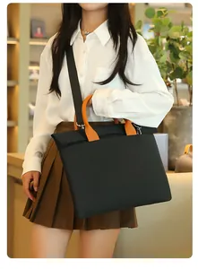 Detail of black business tote bag with orange handles and adjustable nylon shoulder strap