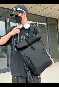 Modern black waterproof roll-top backpack with buckle closure shown in urban city setting
