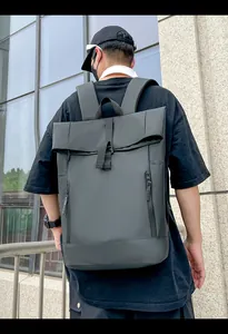 Outdoor shot showing the back view of a black roll-top waterproof commuter backpack on a model