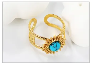 Detail of gold-plated stainless steel ring with turquoise stone and braided texture
