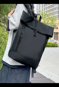 Waterproof roll-top backpack shown from back while worn by a person in city park