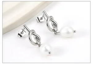Close-up of elegant silver knotted stud earrings with round white pearl drop pendants