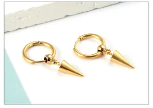 Macro detail of gold stainless steel hoop earrings with spike charms on stone block