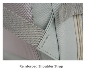 Detail view of reinforced shoulder strap stitching and mesh fabric on grey travel backpack
