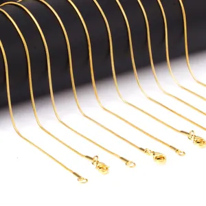 Detailweergave van gouden slangenkettingen met karabijnsluiting op een sieradenstand