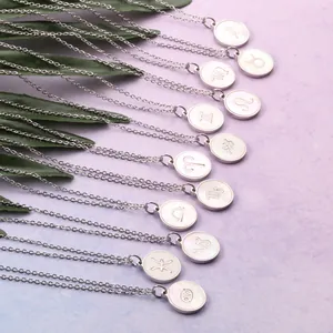 Flat lay of 12 zodiac pendant necklaces with white shell inlay on light purple background