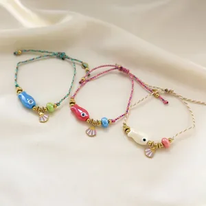 Three-piece ocean style woven bracelet set with ceramic fish and gold shell charms