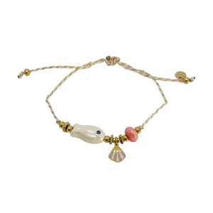 Bohemian ocean style woven bracelet with ceramic fish and shell charms on white background