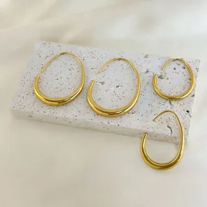 Detailed view of 18K gold plated hollow teardrop earrings on a white stone base