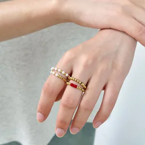 Stackable 18K gold-plated beaded rings with natural stones and white pearls on a hand