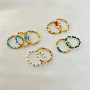 Detailed view of elastic 18K gold plated beaded rings with natural stones on silk fabric