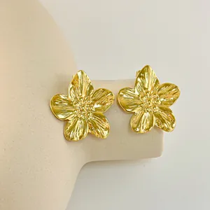 Orecchini a fiore dorati con perla e zircone su sfondo minimalista con petali strutturati