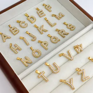 Detailed view of 26 gold-plated letter pendants set with pearls in a wooden jewelry box