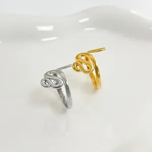Dettaglio di anelli a serpente minimalisti oro e argento su vassoio di ceramica