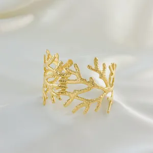 Détail macro du bracelet doré texturé branche sur un fond de tissu en soie blanche