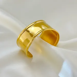 Detailed view of polished 18K gold plated wide wave cuff bracelet on white satin background