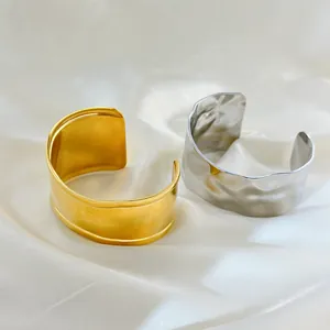 Detail of wavy irregular open bangles in gold and silver finish on silk fabric